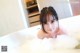 A young woman taking a bath in a bathtub filled with foam.