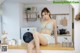 A woman sitting on top of a kitchen counter next to a washing machine.