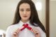 A woman in a white shirt is tying a red tie.