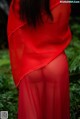 A woman in a red dress standing in the woods.
