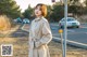 A woman standing on the side of a road next to a street sign.