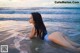 A woman in a blue bikini laying in the ocean.