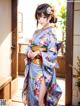 A woman in a blue kimono standing in a room.