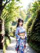 A woman in a blue kimono walking down a path.