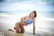 A woman in a blue bikini sitting in the water.