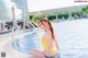 A woman in a yellow bathing suit sitting in a pool.