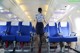 A woman standing in the aisle of an airplane.