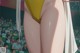 A woman in a yellow bikini standing in front of a crowd.